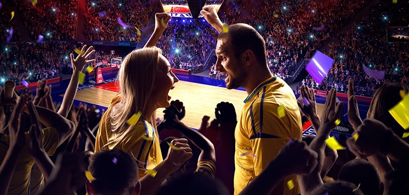 Una coppia presso un palazzetto mentre assiste ad una partita di basket esultando per la propria squadra di backet