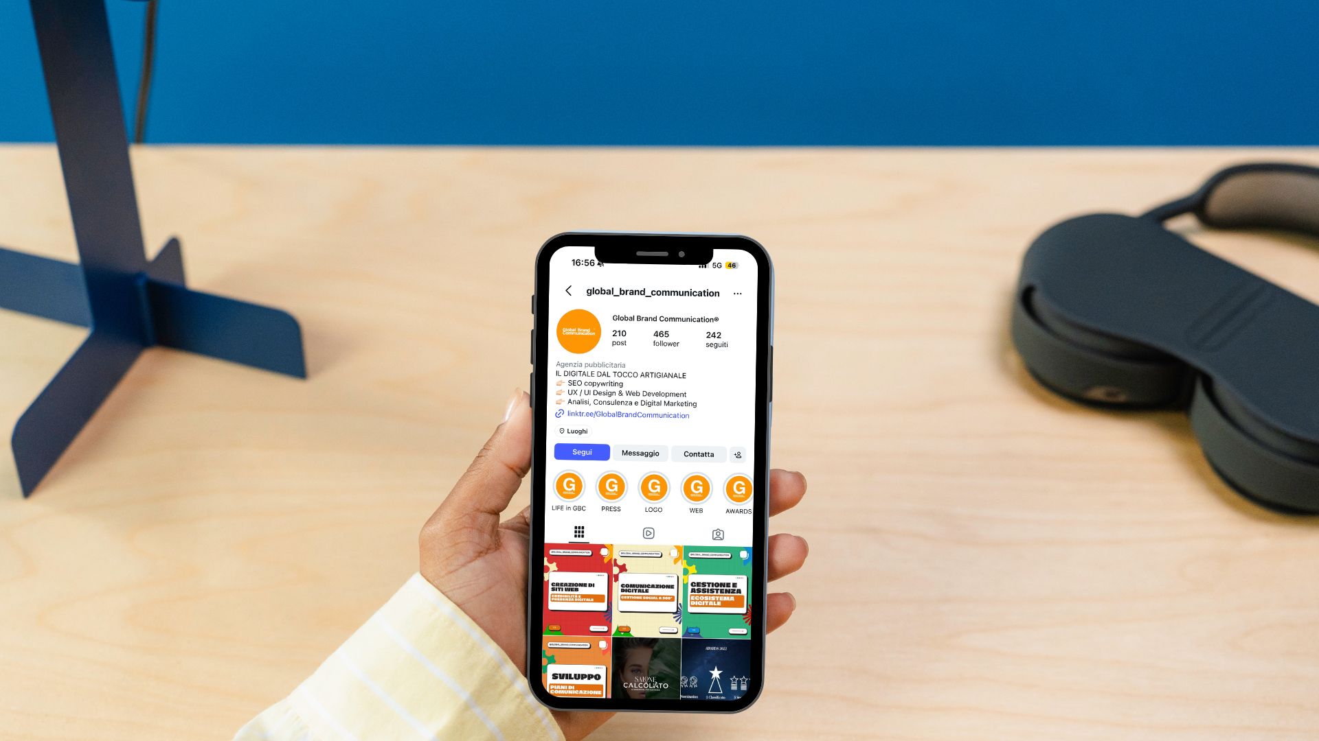 Uno smartphone in mano che mostra il profilo Instagram di Global Brand Communication, con la griglia dei post pubblicati